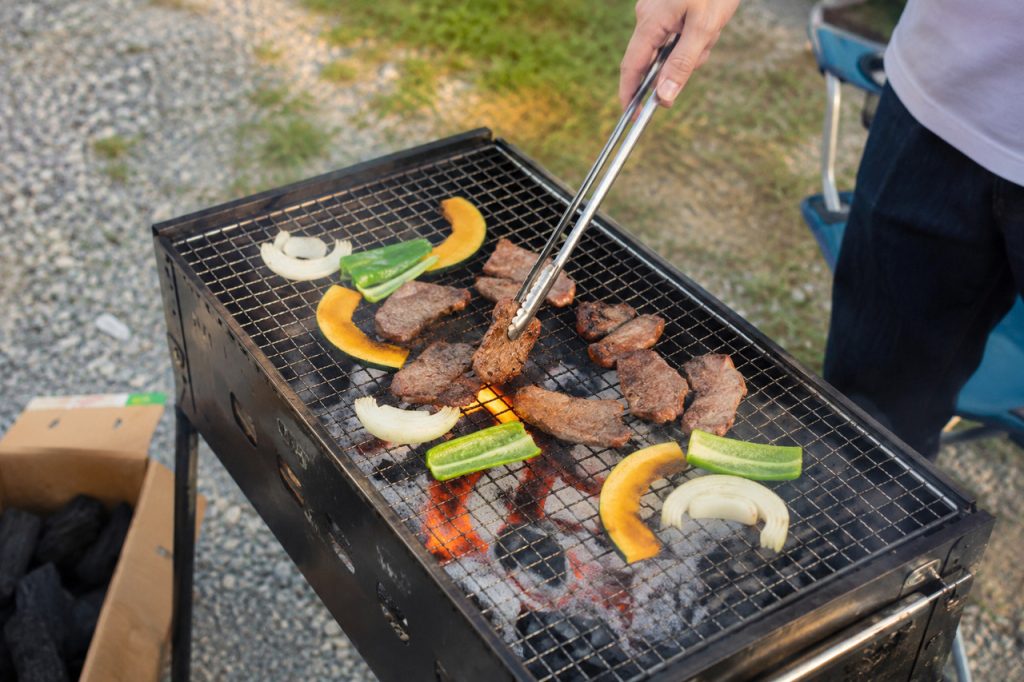 炭火バーベキューコンロで肉と野菜を焼いている様子